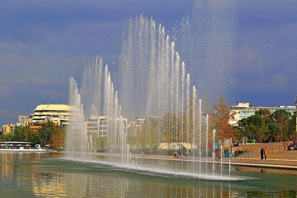 The dancing fountains along the SNFCC canal in golden light, the Renzo Piano building behind