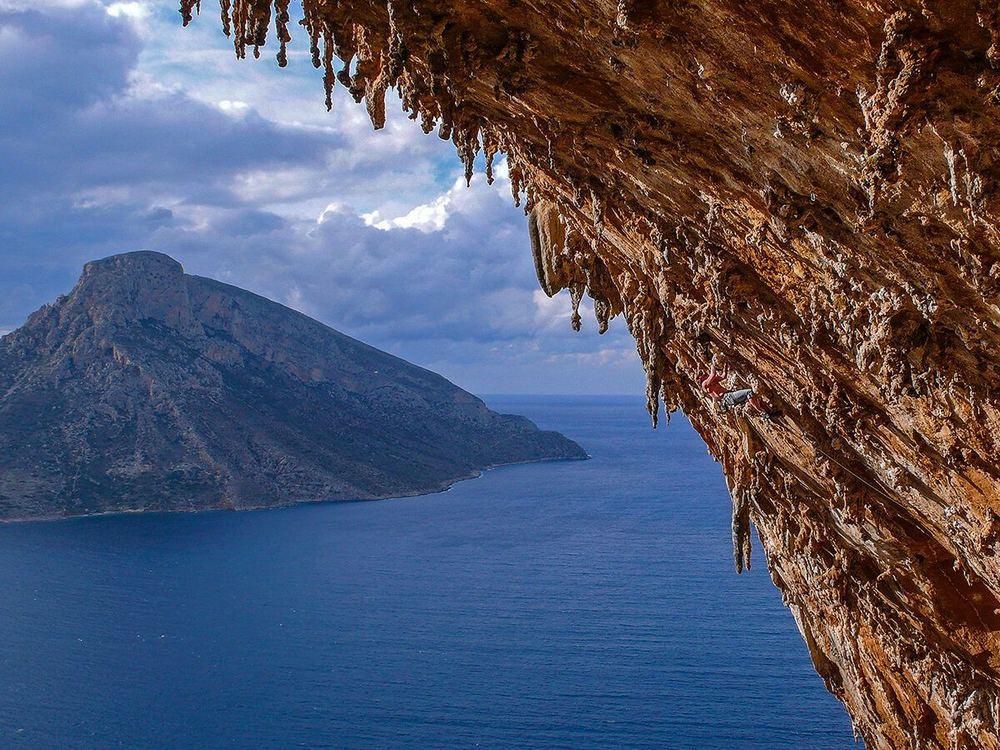 A climber high in the Grande Grotta above Massouri, Telendos across the water