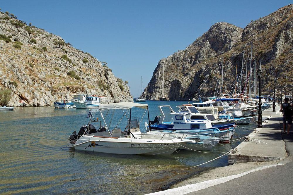 The narrow blue-green inlet of Vathy with fishing boats moored below the cliffs