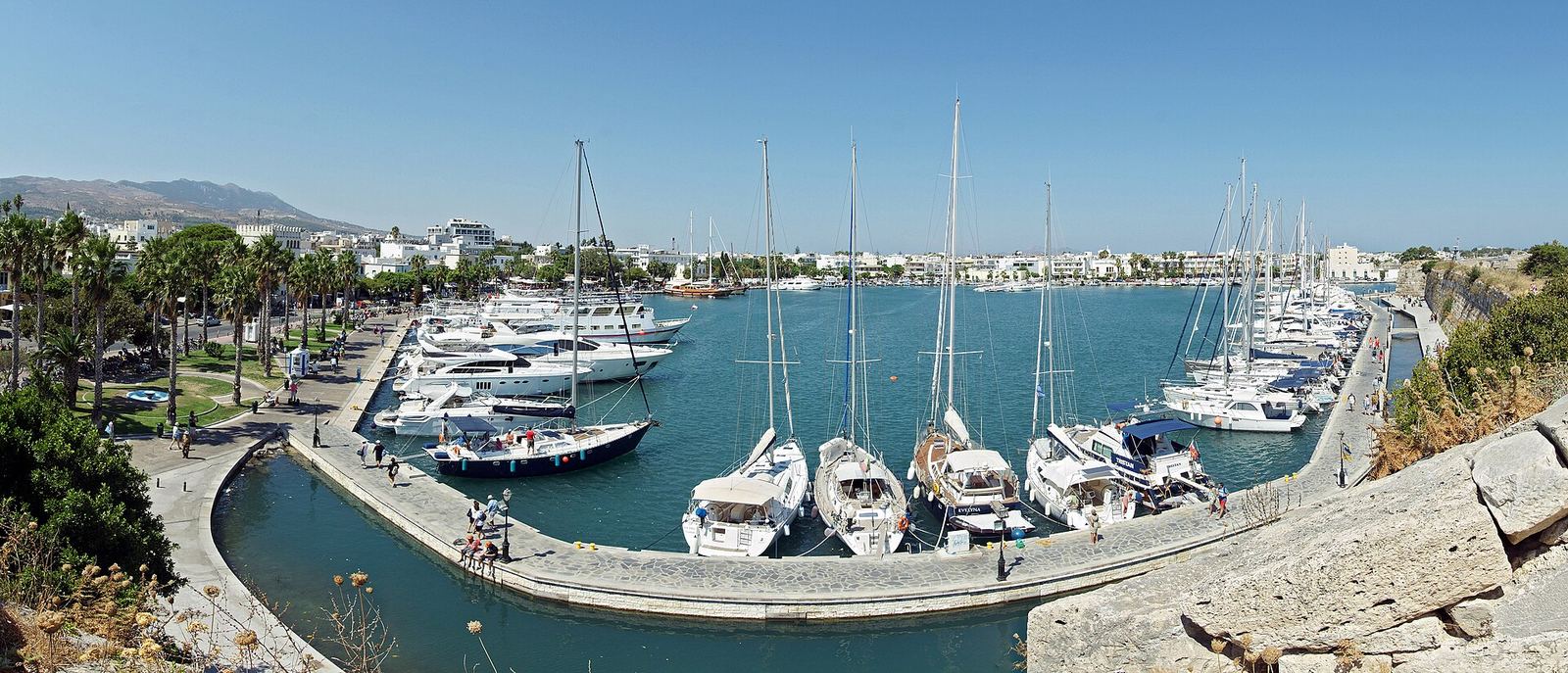 Kos town's inner marina: rows of yachts, palms, and the wall of Neratzia castle
