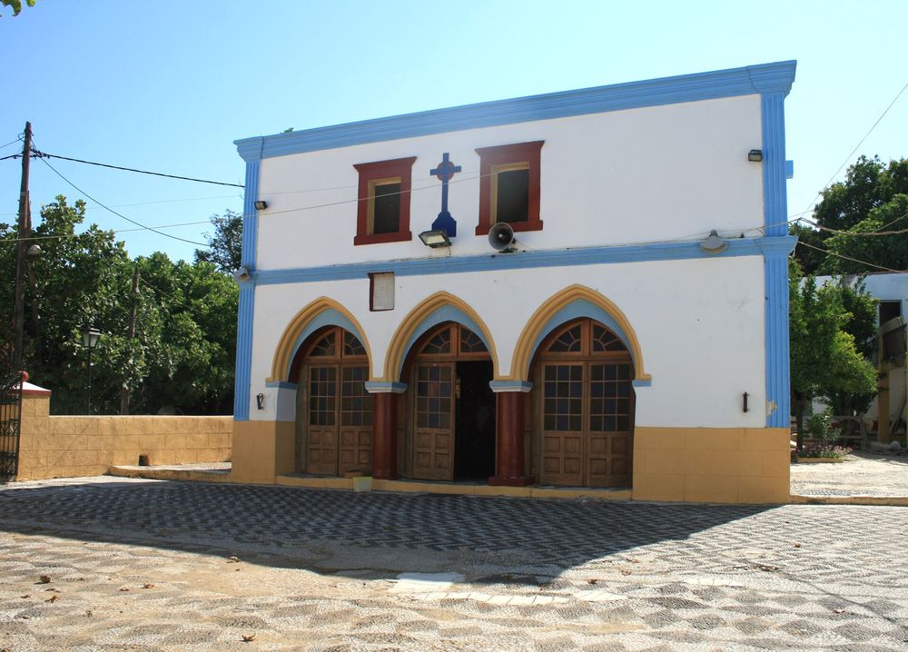 A blue-and-white church on the cobbled square of Zia village