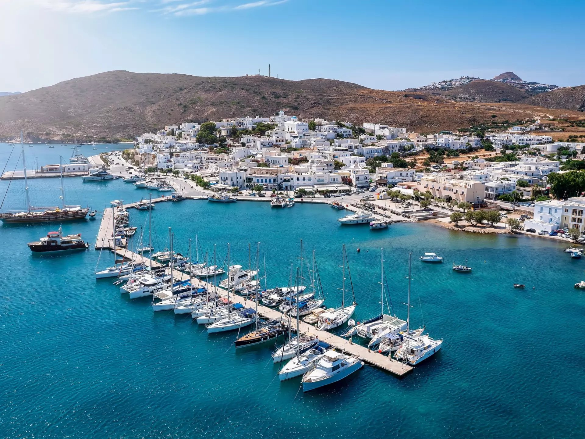Aerial view of Adamas on Milos: yachts and small boats along the quay inside the wide volcanic bay