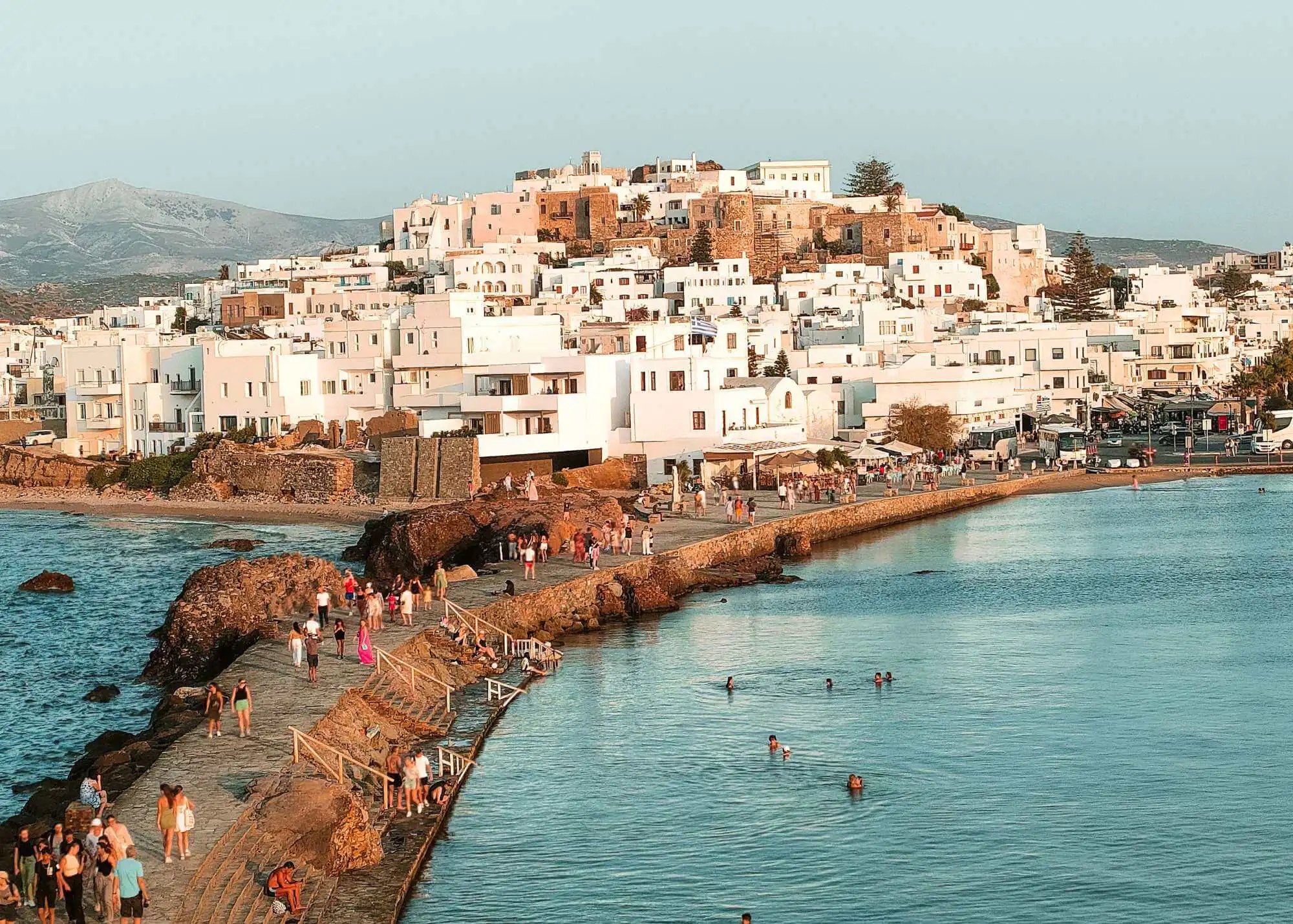 The sandy causeway at Naxos town with shallow water on both sides and the old town behind