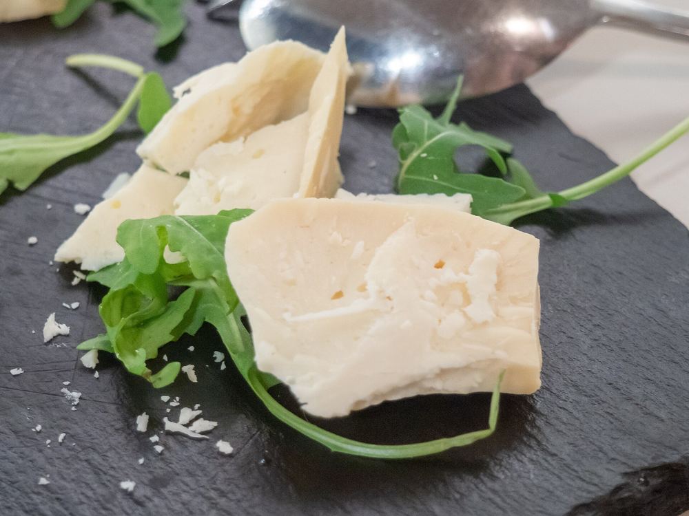 Wedges of Arseniko Naxou, a Naxos protected-origin cheese, on slate with arugula