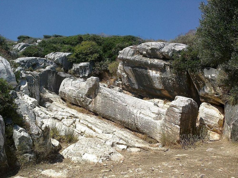 A kouros, a giant unfinished marble statue, lying in the ancient quarry where it was carved